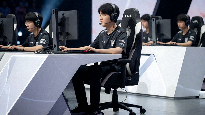 LPL英雄联盟季后赛现场，EDward Gaming队员在赛事舞台灯光下坐在各自的比赛席位上竞技